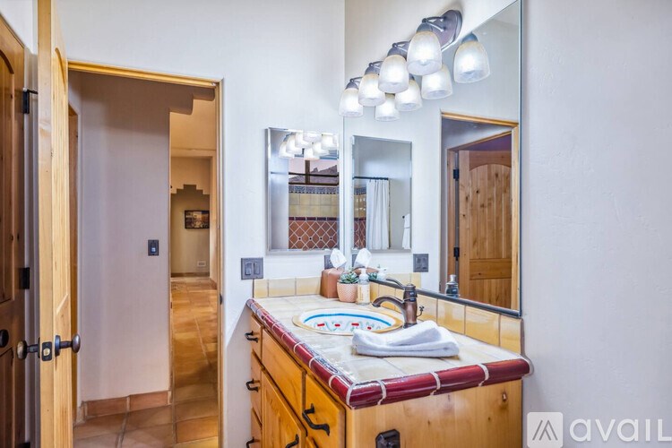 A bathroom with a wooden vanity and a large mirror above it.