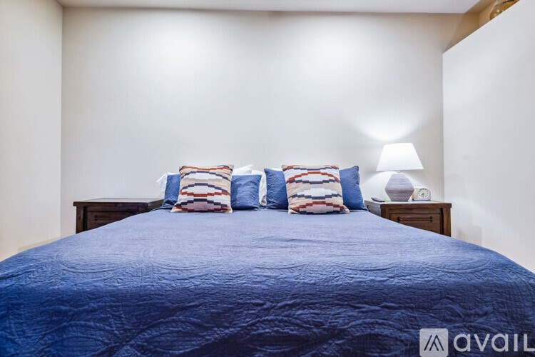 A bed with a blue comforter and striped pillows.