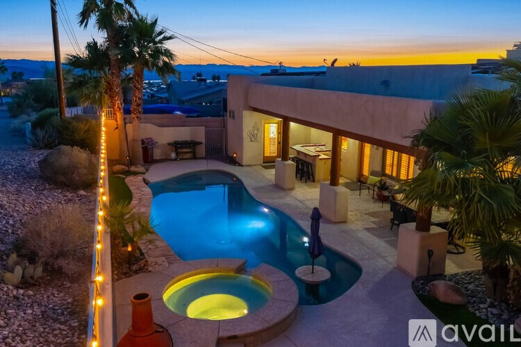 A house with a pool and palm trees in front.