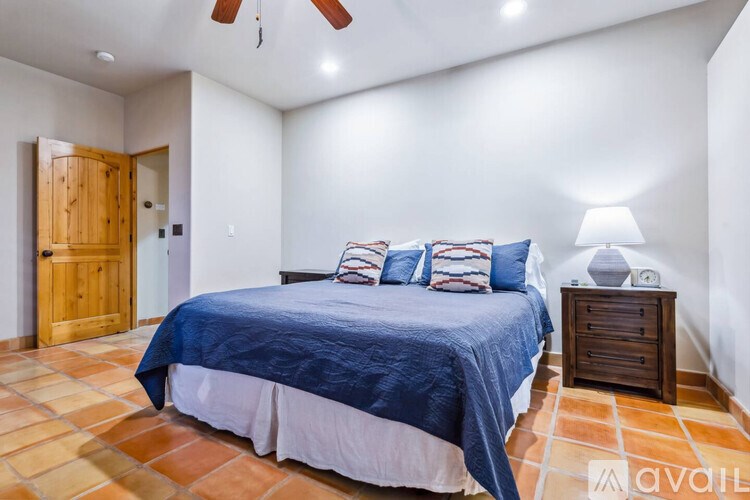 A bedroom with a bed, pillows, and a ceiling fan.
