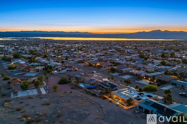 A sunset view of a city with buildings and a mountain range in the background.