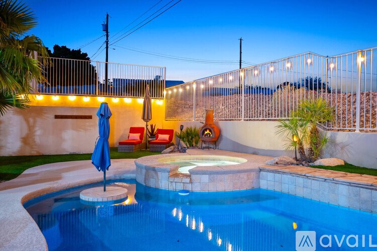 A pool with a lit up fence and a blue umbrella.