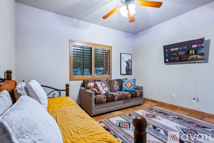 A bedroom with a bed, couch, and a ceiling fan.