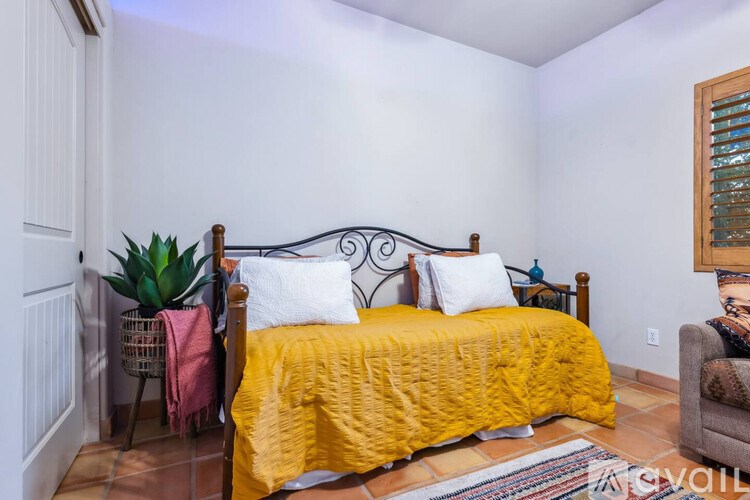 A bedroom with a bed covered in a yellow comforter.