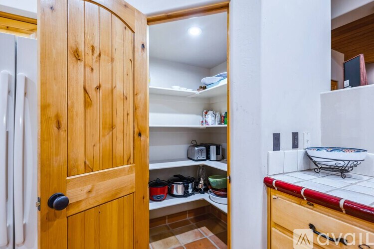 A kitchen with a wooden door and a white fridge.