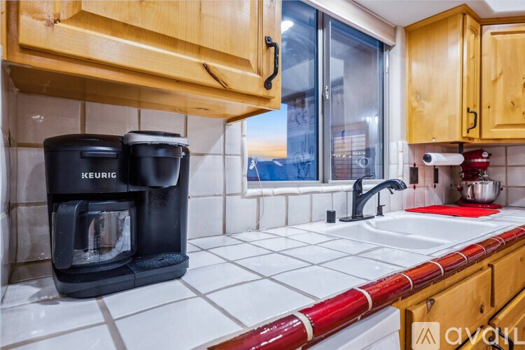 A kitchen with a black coffee maker and a red and white striped counter.