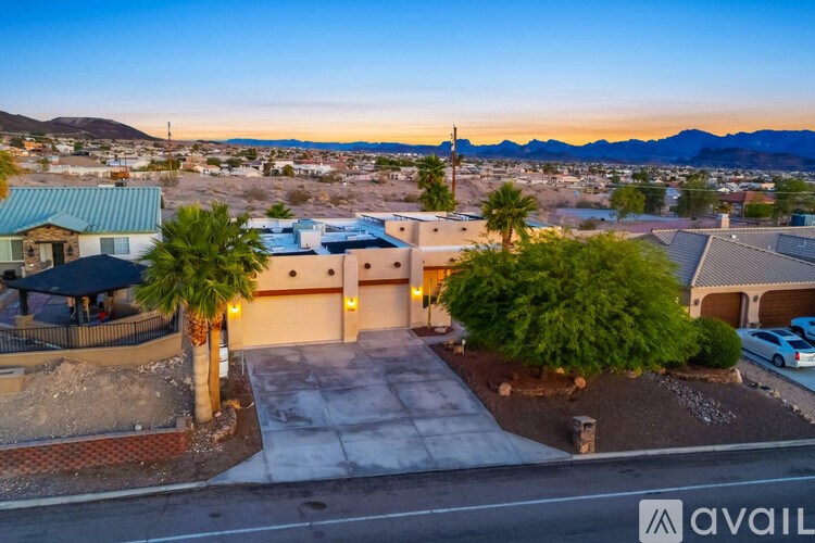 A house with a driveway and palm trees in front of it.