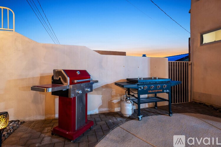 A red barbecue grill is on a patio with a pool table.