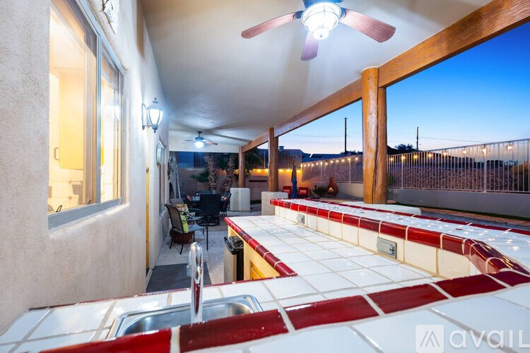 A patio with a red and white tile border and a ceiling fan.