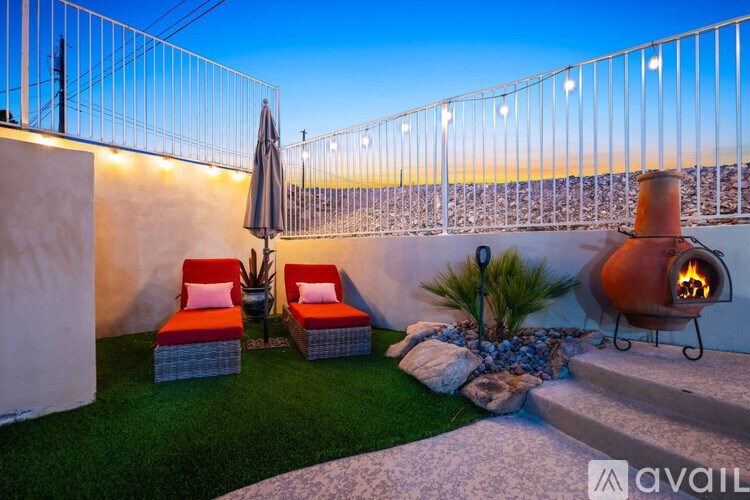 A patio with a fire pit, chairs, and a table with a plant on it.