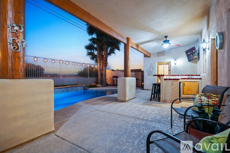 A patio with a table and chairs overlooking a pool.