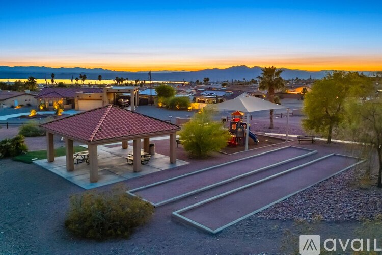 A gazebo is surrounded by a gravel area and a playground.