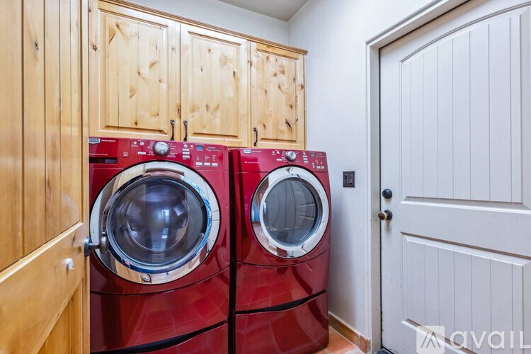 Two red front load washing machines in a laundry room.