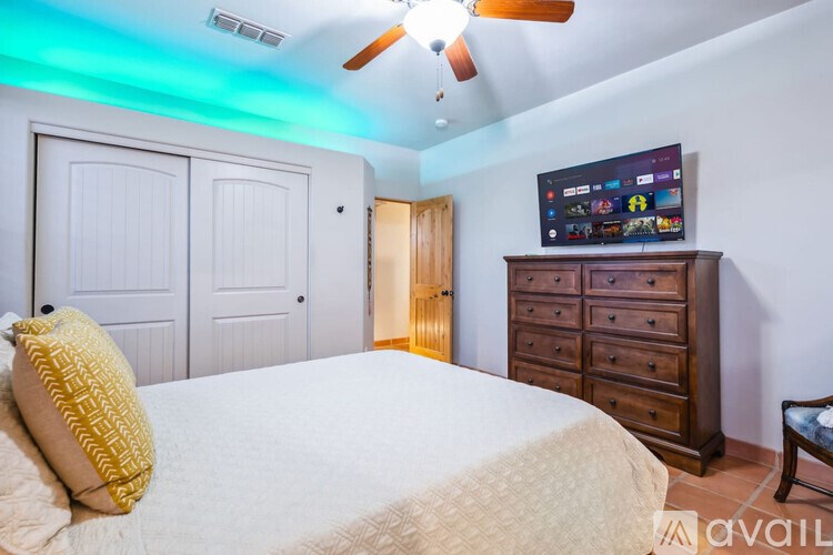 A bedroom with a bed, dresser, and ceiling fan.
