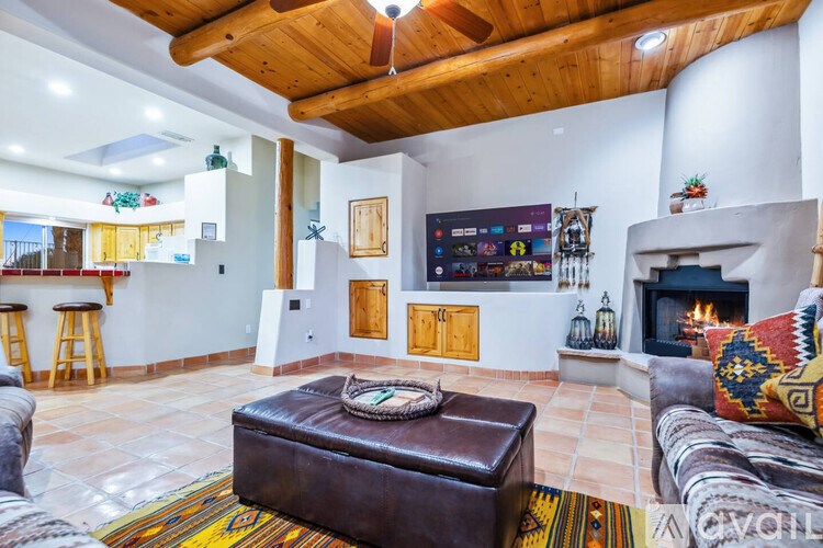 A living room with a brown leather ottoman and a fireplace.
