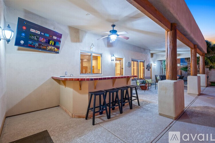 A bar area with stools and a television on the wall.