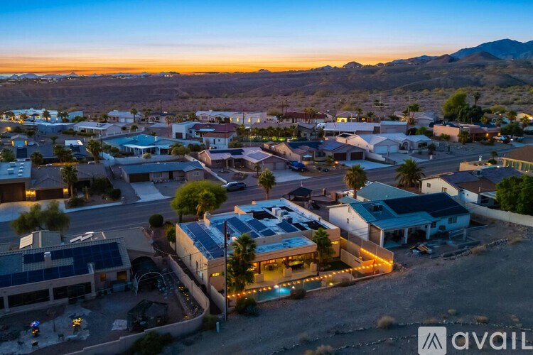 A sunset view of a small town with buildings and streets illuminated by streetlights.