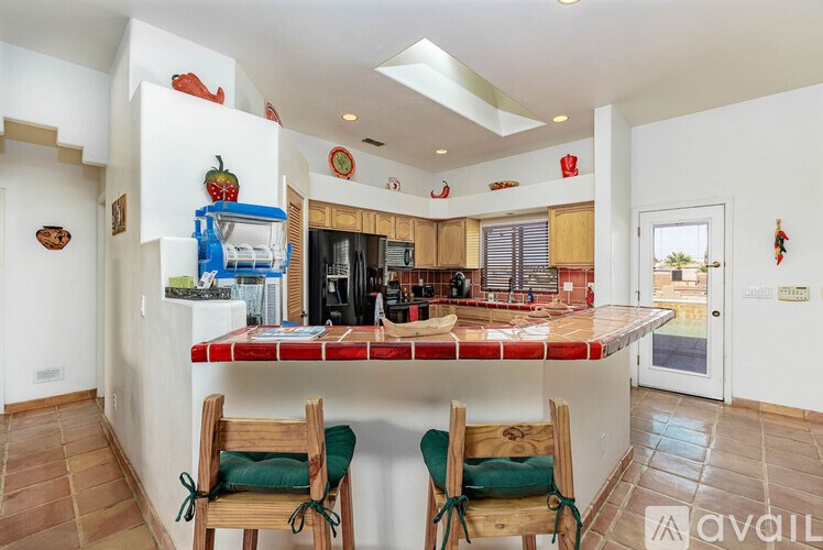 A kitchen with a red tile backsplash and wooden chairs.