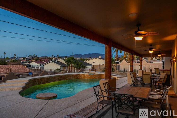 A patio with a table and chairs overlooking a pool and a view of the mountains.