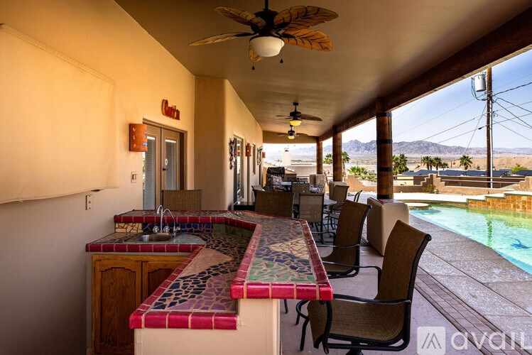 A patio with a table and chairs overlooking a pool.