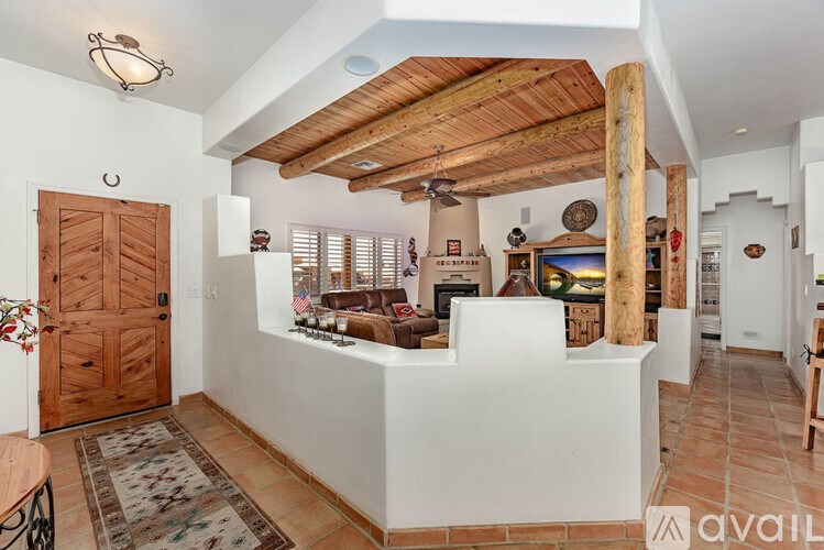A living room with a wooden ceiling beam and a rug on the floor.