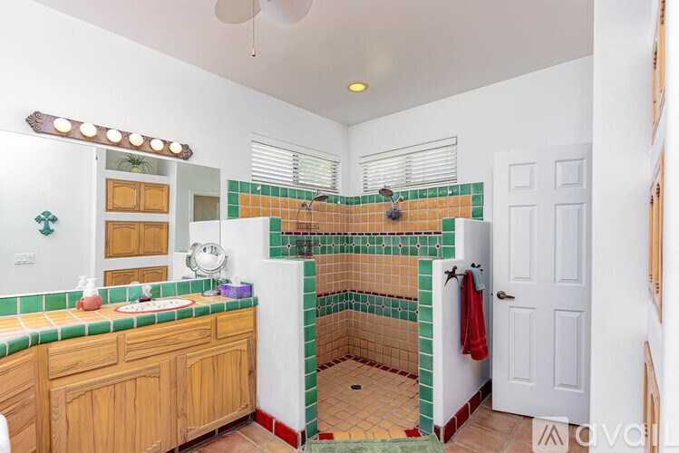 A bathroom with a green and white tiled shower area.