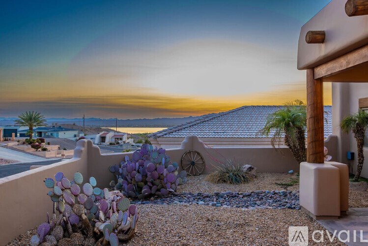 A house with a garden in front and a sunset in the background.