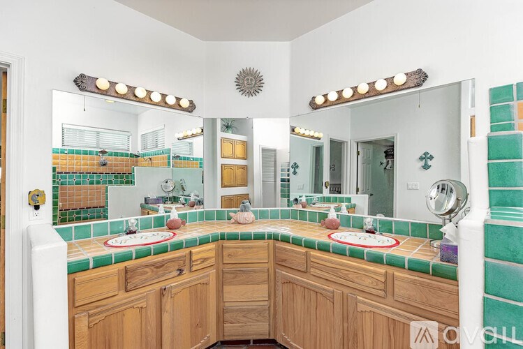A bathroom with green tiles and wooden cabinets.