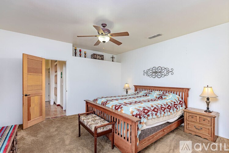 A bedroom with a bed, a bench, and a ceiling fan.