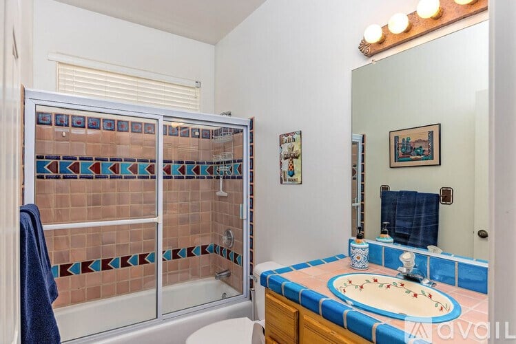 A bathroom with a blue and pink tiled shower and a matching sink.