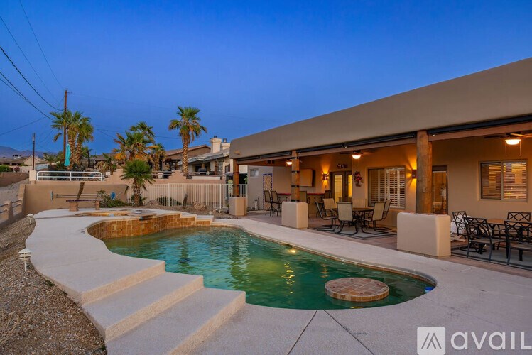 A pool with a hot tub and a house with a patio.