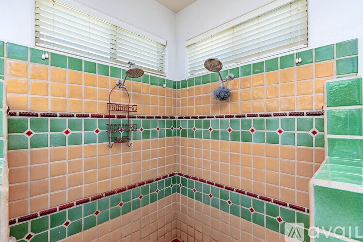 A bathroom with a green, orange and red tiled shower.