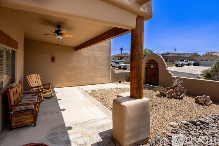 A patio with a ceiling fan and two chairs.