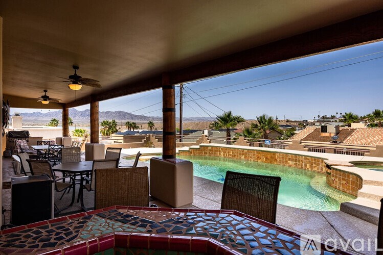 A pool area with a table and chairs and a ceiling fan.