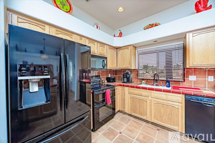 A kitchen with a black refrigerator and wooden cabinets.