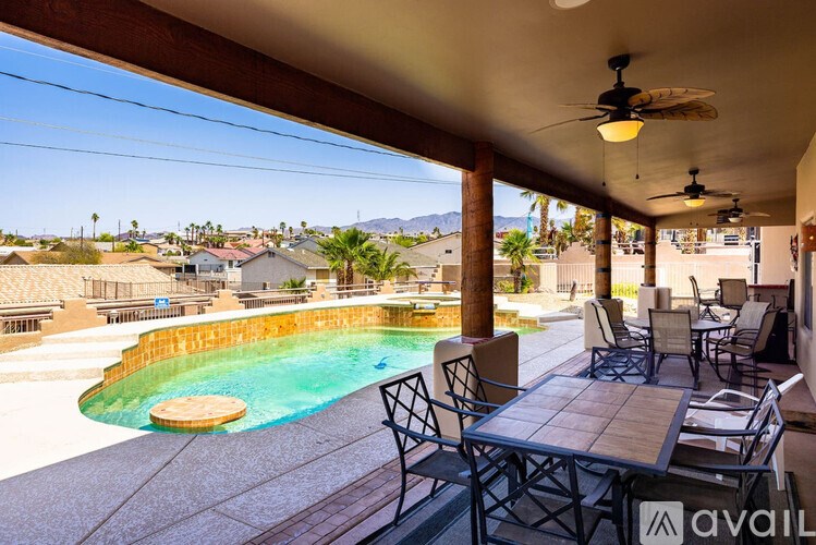 A patio with a table and chairs overlooking a pool.