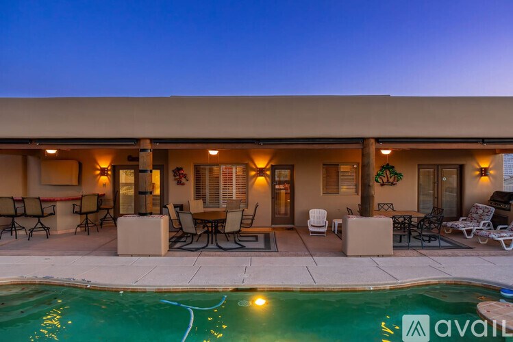 A poolside patio area of a house with a pool and furniture.