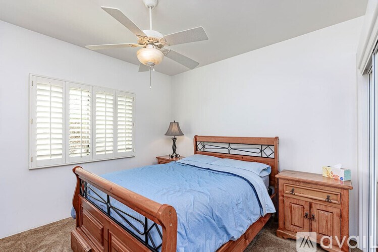 A bedroom with a bed, nightstand, and window with blinds.