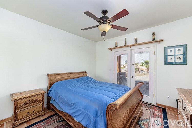 A bedroom with a bed, dresser, and ceiling fan.