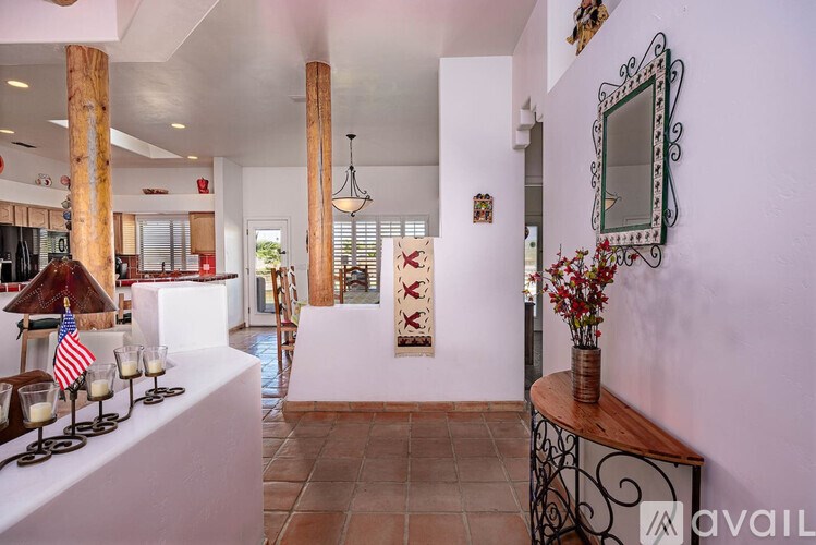 A white room with a mirror and a vase of flowers.