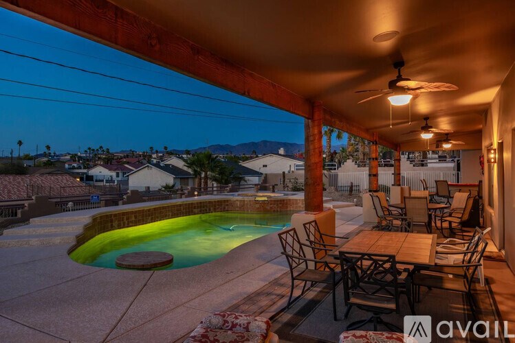 A patio with a table and chairs overlooking a pool.