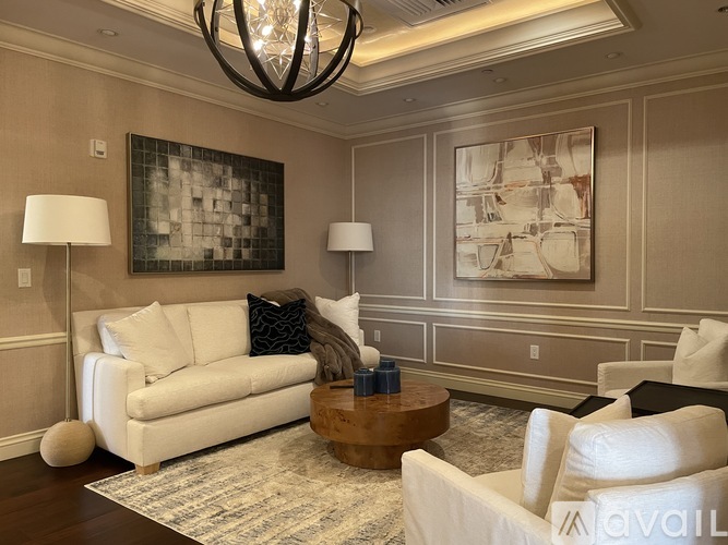 A living room with a white sofa, a wooden coffee table, and a chandelier.
