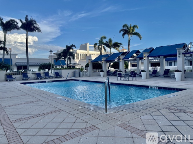 A pool surrounded by palm trees and lounge chairs.