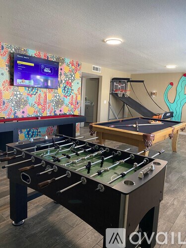 A foosball table is in a room with a basketball hoop and a TV.