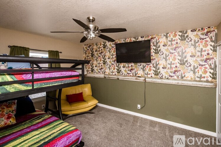 A room with a bunk bed, a chair, and a wallpapered wall.