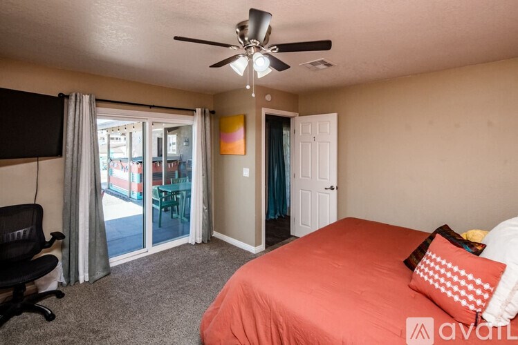 A bedroom with a bed, chair, and sliding glass doors.