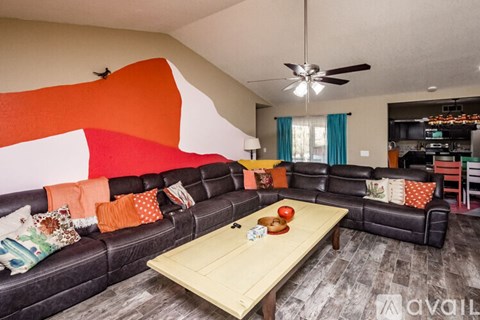 A living room with a black couch and a wooden coffee table.