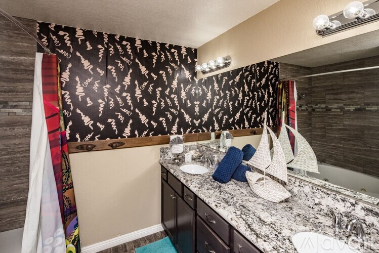 A bathroom with a maritime theme, featuring a white sink, a mirror, and a shower curtain with a sailboat design.
