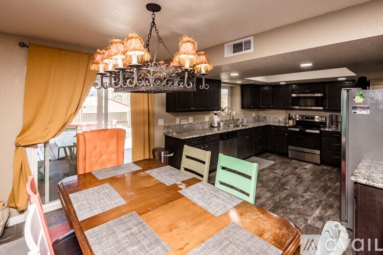A kitchen with a table and chairs in the foreground and a refrigerator in the background.