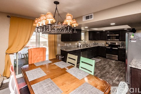 A kitchen with a table and chairs in the foreground and a refrigerator in the background.